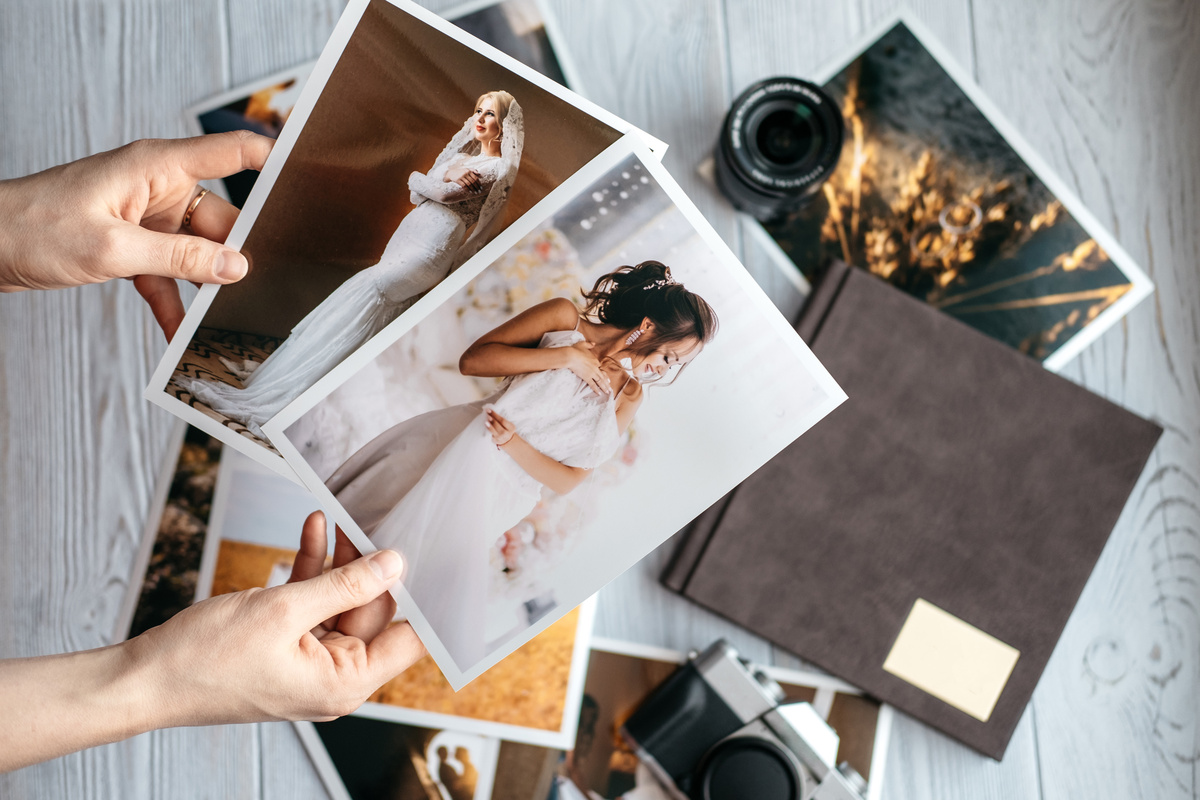 Mãos segurando fotos de um casamento