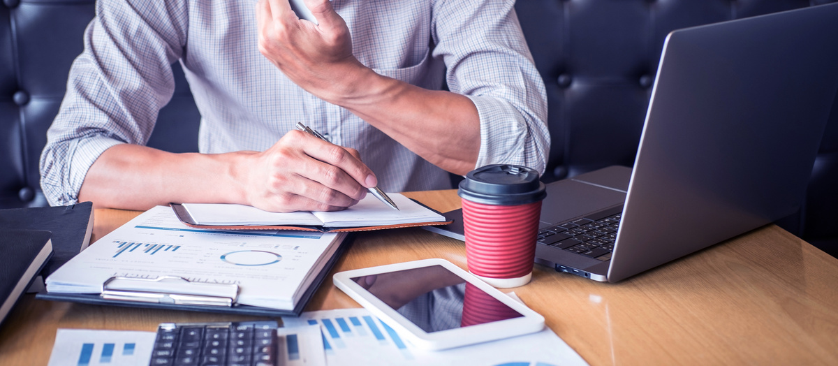 Homem focado no trabalho com notebook, celular e gráficos