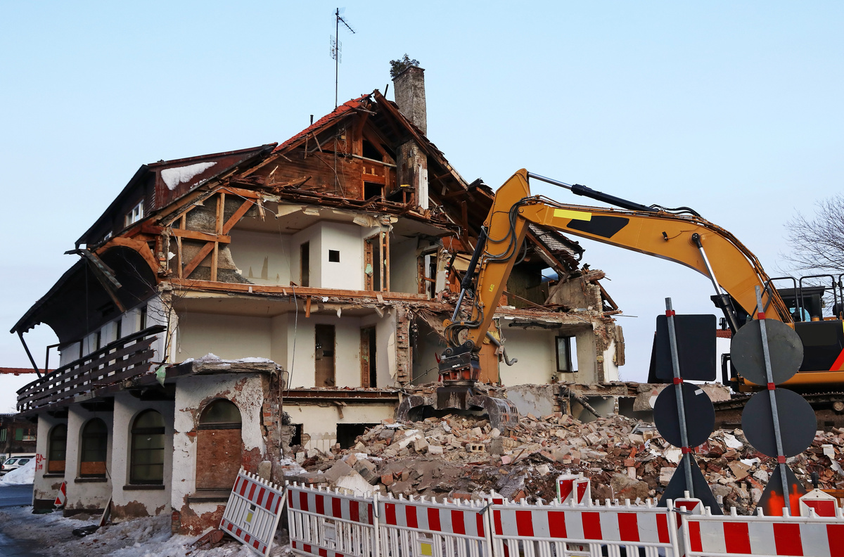 Casa sendo destruída por trator.