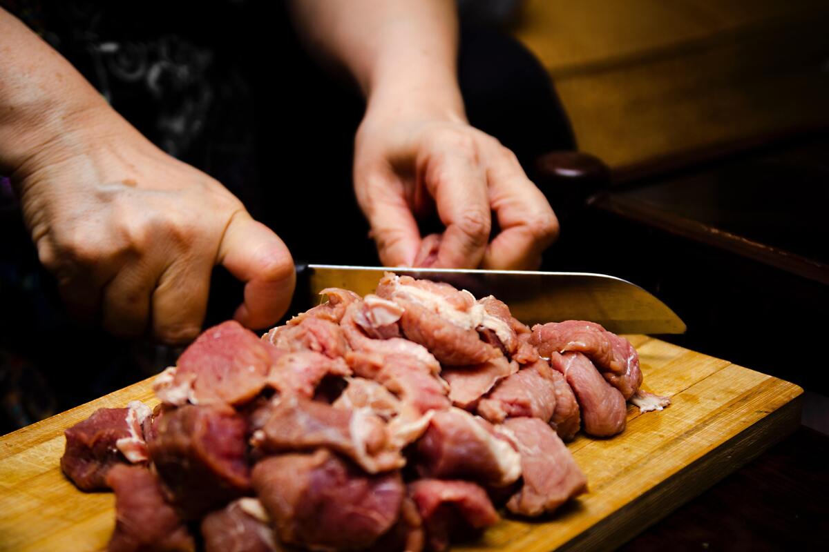 Homem cortando carne crua.