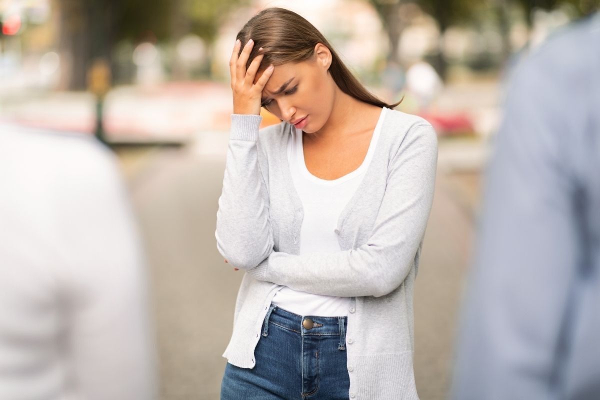 Mulher pensativa, com uma mão na cabeça