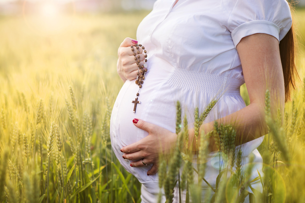 Mulher grávida em vegetação com um terço