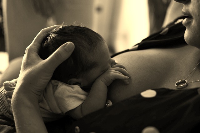 Bebê deitado no colo da mãe e mamando