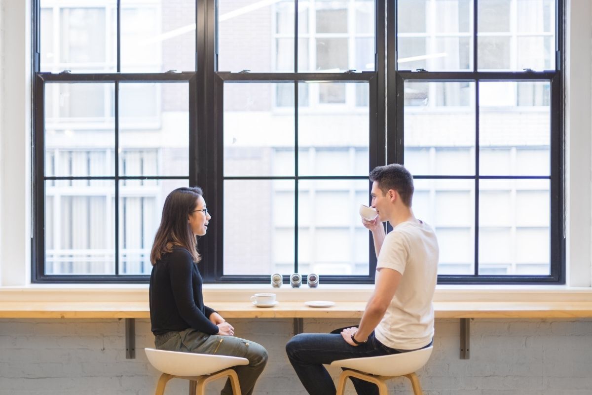 Mulher e homem conversando e tomando um café