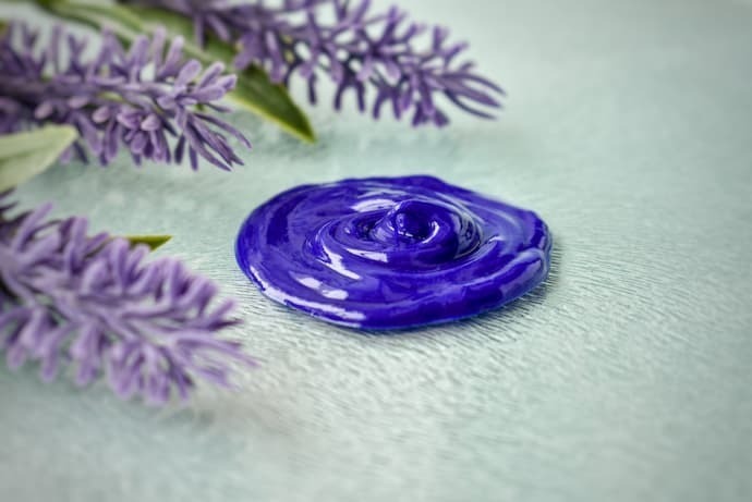 Creme matizador roxo ao lado de flores roxas