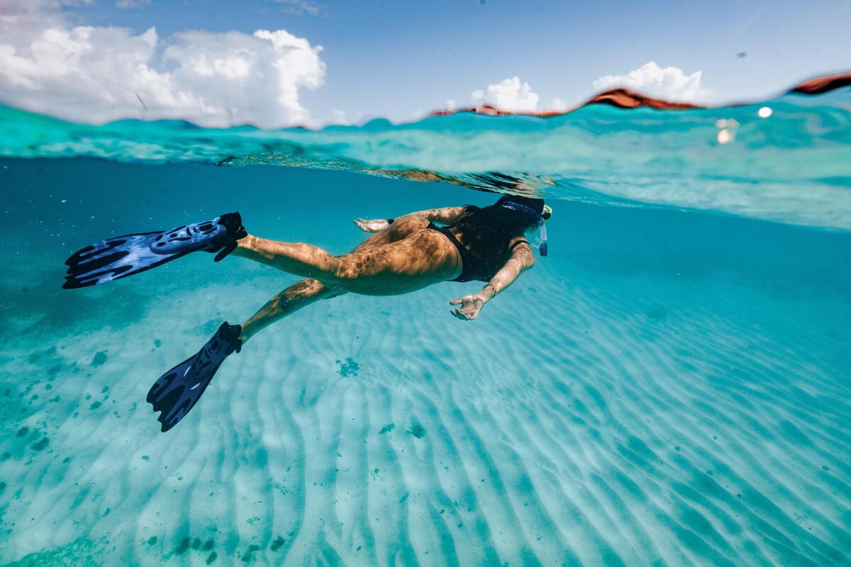 Mulher mergulhando em mar com pés de pato. 