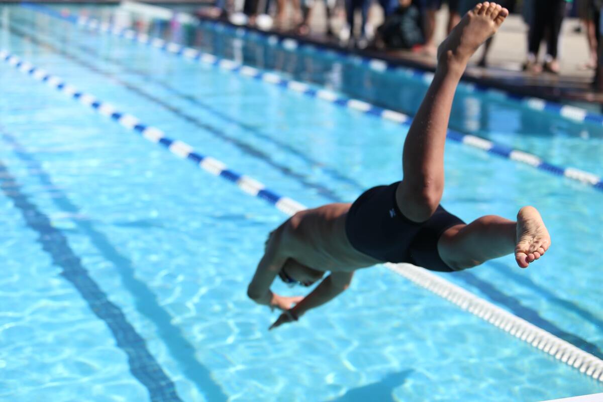 Homem mergulhando em piscina. 