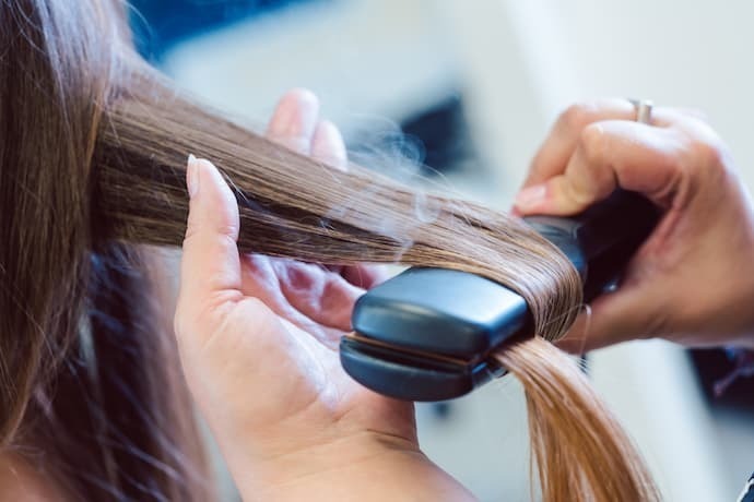 Fumaça saindo de chapinha enquanto é passada no cabelo