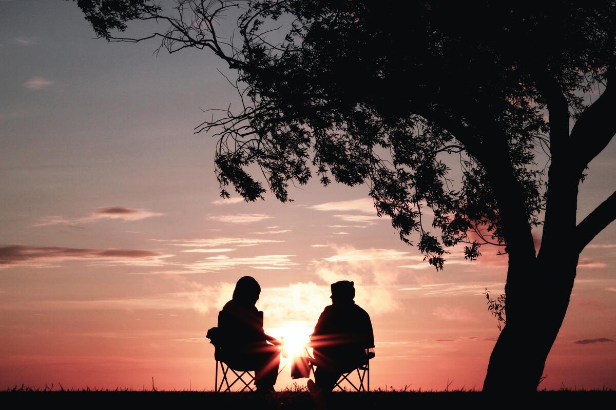 Casal sentado vendo o por do sol. 