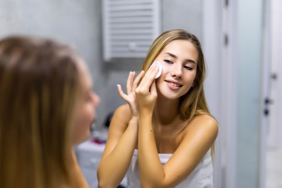 Mulher aplicando tônico facial algodão