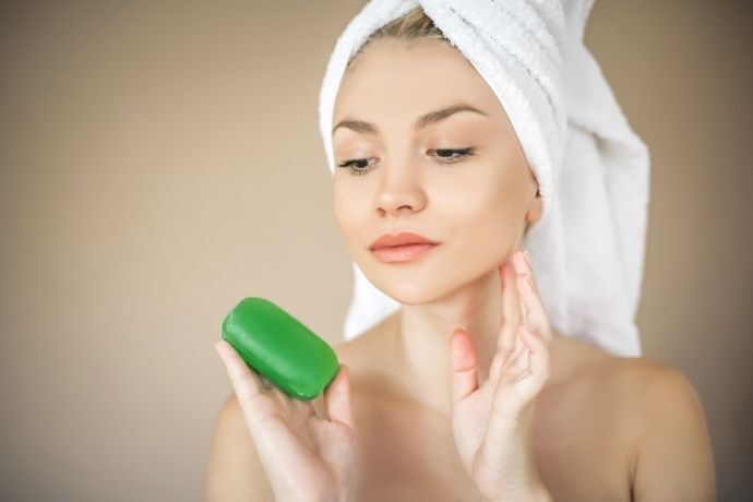 Mulher com toalha no cabelo olhando para sabonete verde