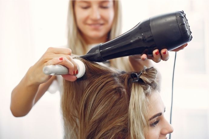 Mulher pasando o secador no cabelo e outra