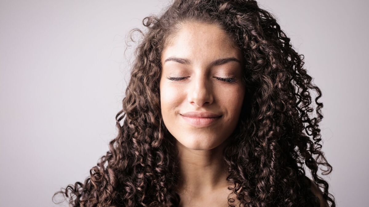 Mulher feliz com cabelo cacheado.