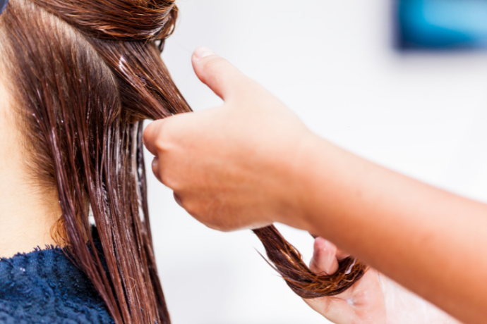 Cabeleireiro aplicando progressiva em cabelo.