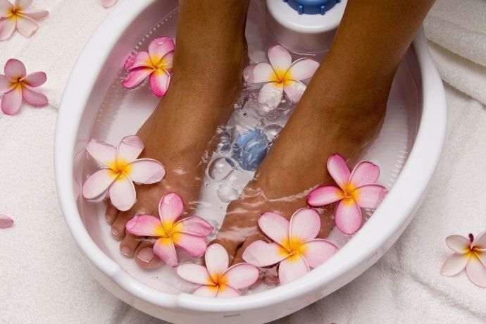 Pés femininos em spa para os pés com flores