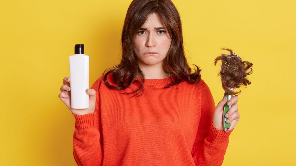 Mulher segurando shampoo e escova com cabelo.