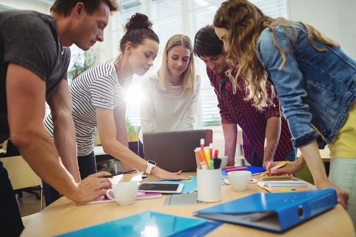 Diversas pessoas reunidas ao redor de computador, representando as diversas formas de relacionamento, o que envolve os signos de Câncer e Gêmeos.