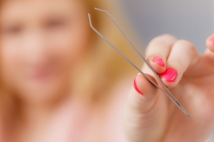 Mulher segurando pinça de sobrancelhas