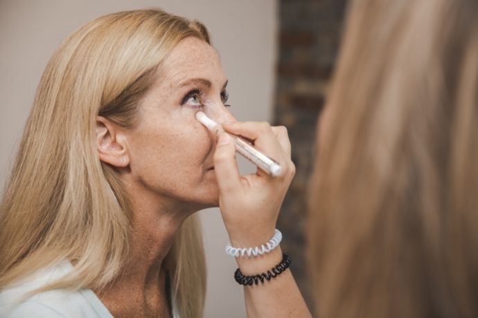 Senhora aplicando creme para olheiras em bastão