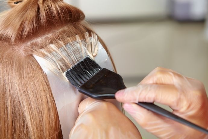 Pessoa pintando o cabelo de mulher com pincel