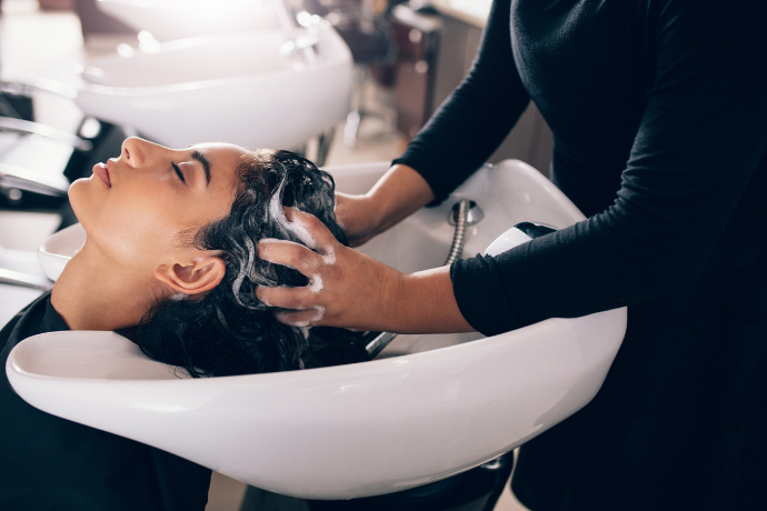 Mulher lavando cabelo em cabeleireiro.