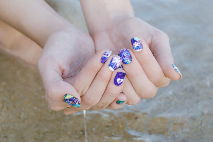 Unhas decoradas com adesivos.