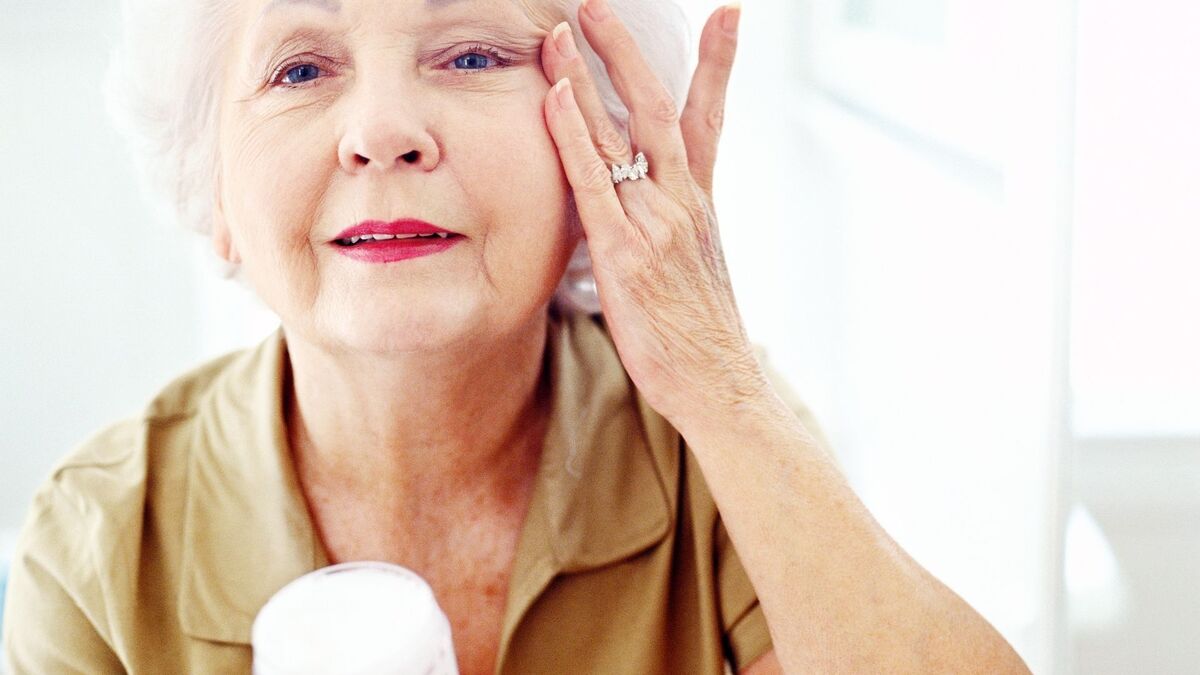 Mulher passando creme para rugas no rosto.