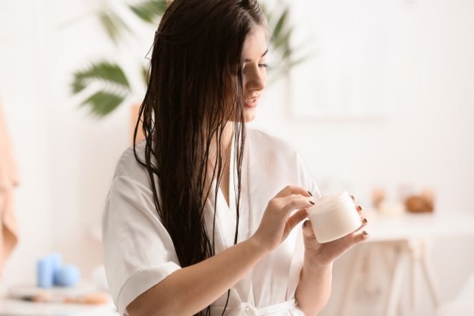 Mulher pegando creme para passar no cabelo