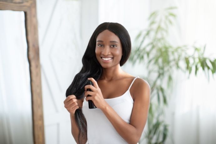 Mulher aplicando óleo no cabelo com spray