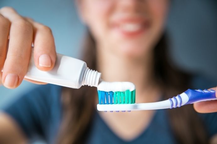 Mulher colocando pasta de dente em escova de dente