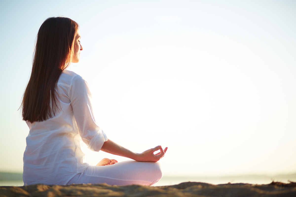 Mulher meditando sentada em pedra