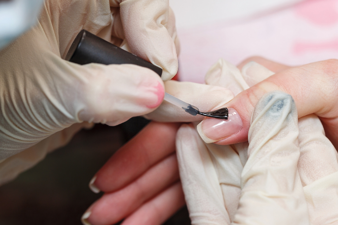 Mulher pintando unhas em francesinha.