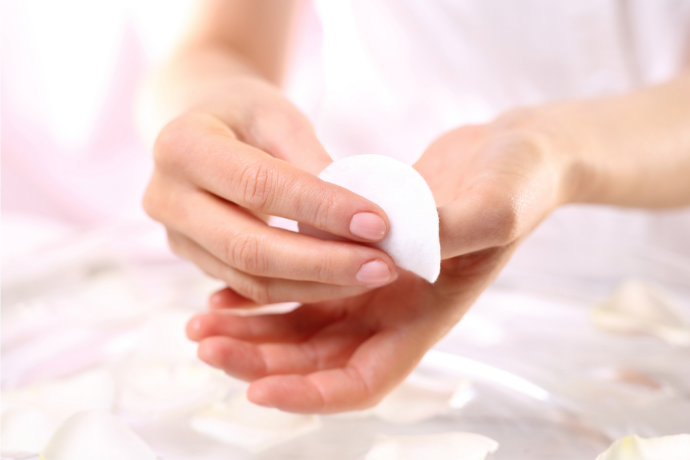 Mulher aplicando removedor de esmalte nas unhas.