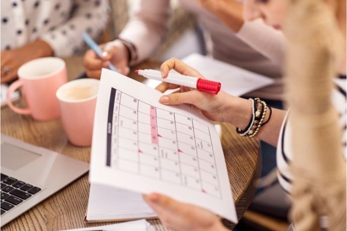 Mulher segurando calendário e caneta vermelha