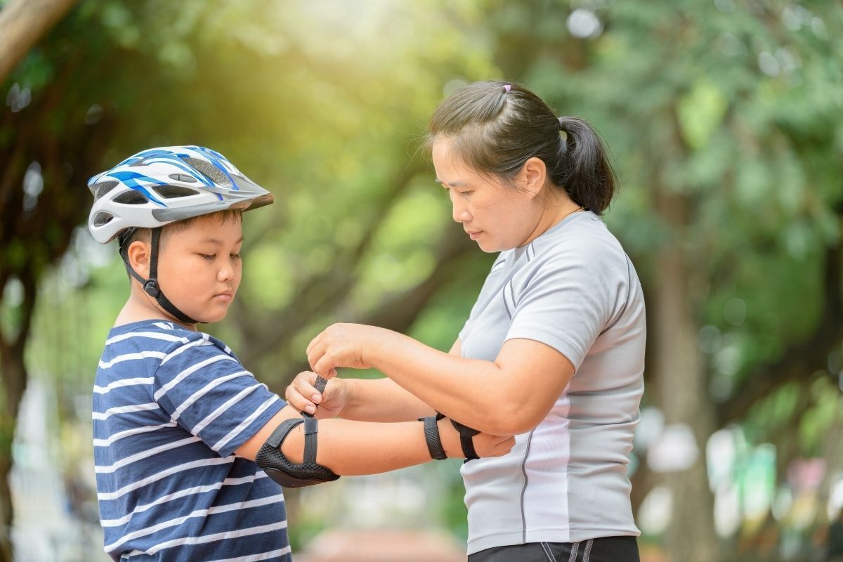 Mãe colocando roupas de proteção em filho.