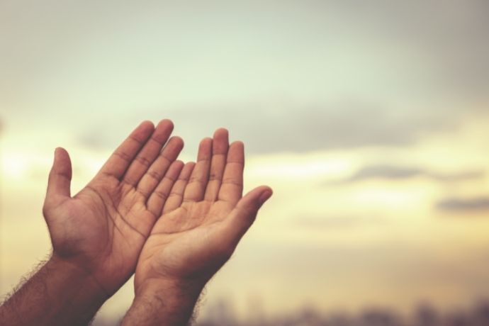 Mãos erguidas para o céu em sinal de oração