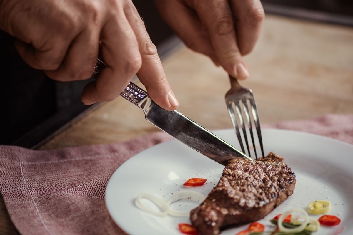 Pessoa comendo bife.