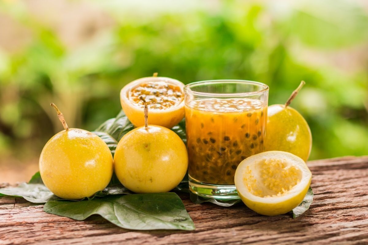 Maracujás abertos e suco de maracujá em copo.