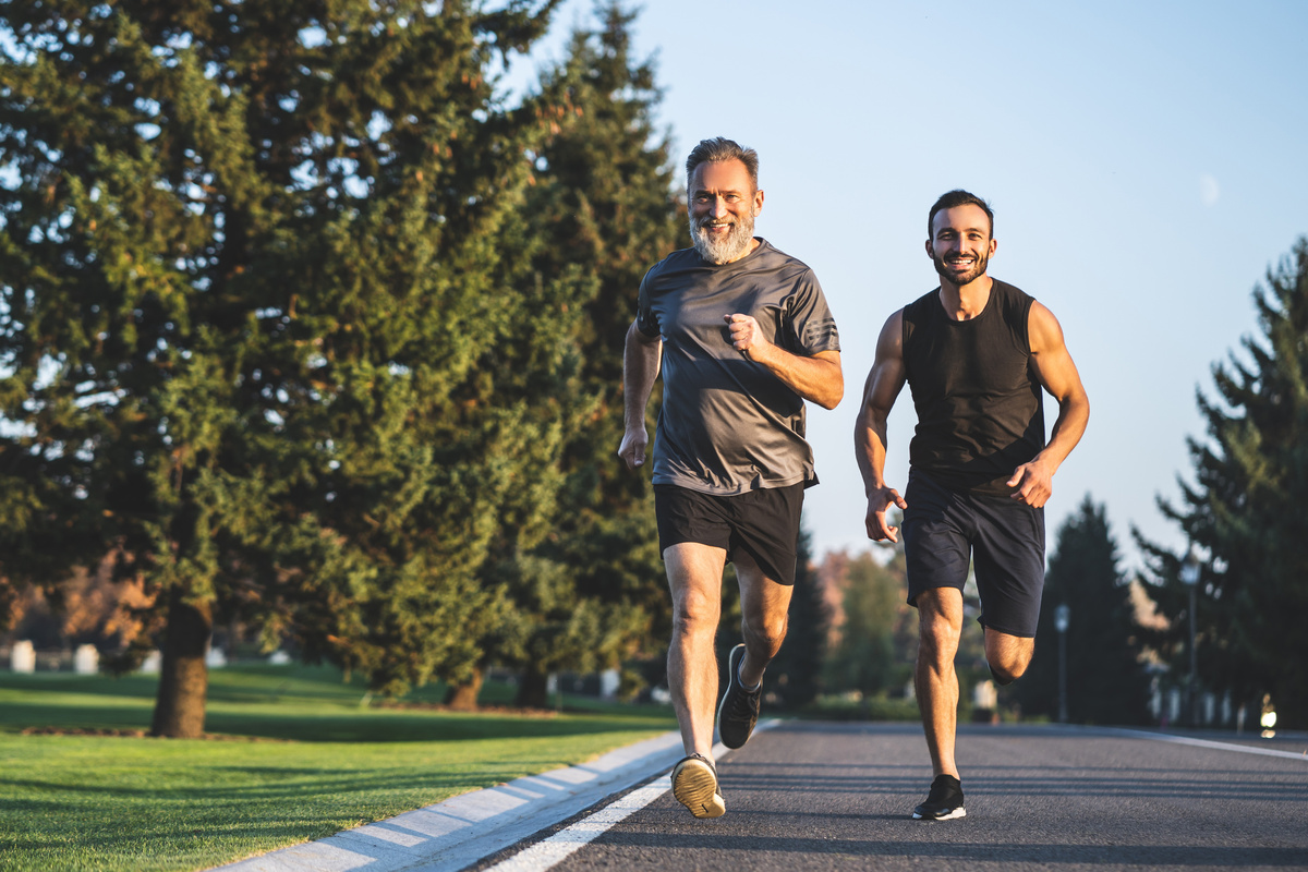 Dois homens praticando corrida na calçada