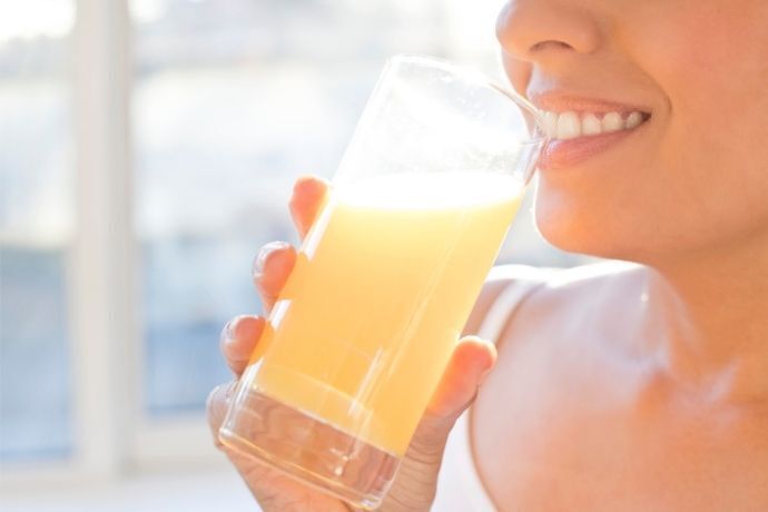 Mulher tomando suco de laranja