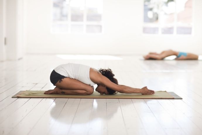 Mulher deitada em tapete fazendo yoga