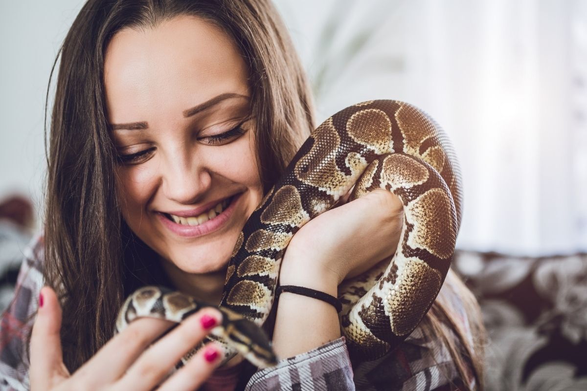 Mulher com cobra de estimação no ombro.