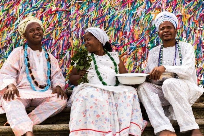 Pessoas com roupas brancas sentadas na frente das fitas na Igreja do Senhor do Bonfim