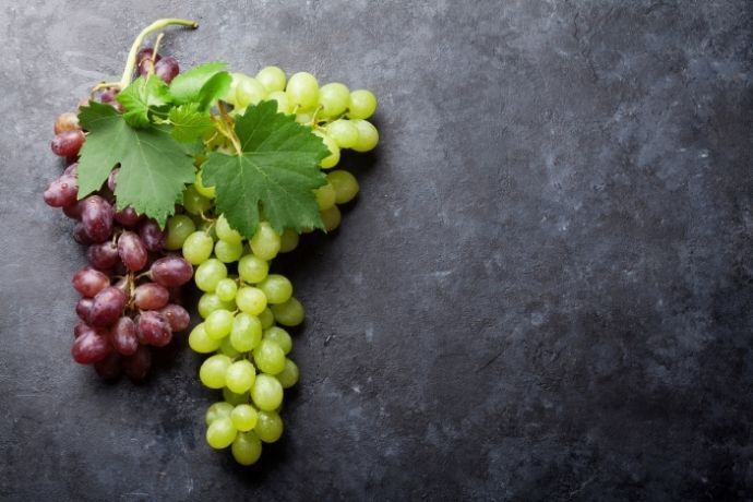 Cachos de uva verde e roxa em superfície cinza