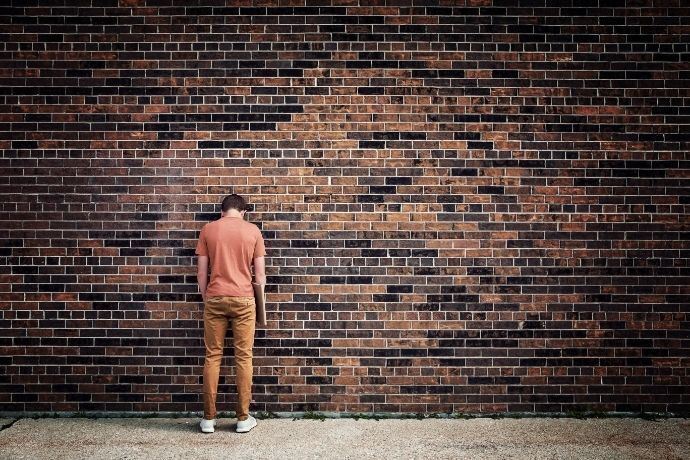 Homem de frente para muro de tijolos