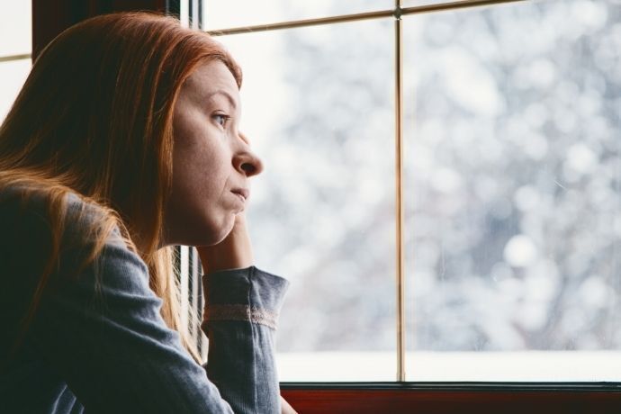 Mulher olhando triste por janela de vidro