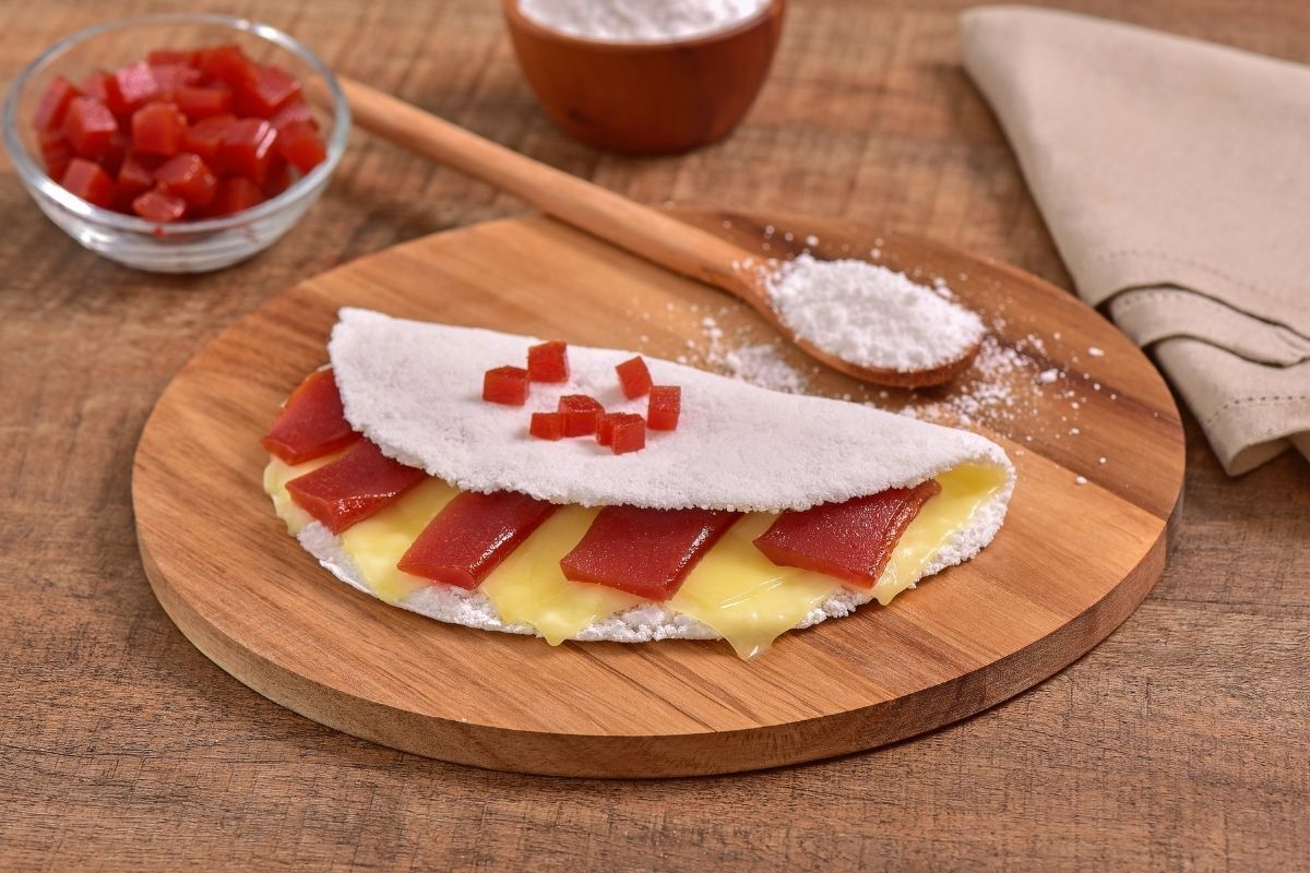 Tapioca com queijo e goiabada em tábua de madeira.