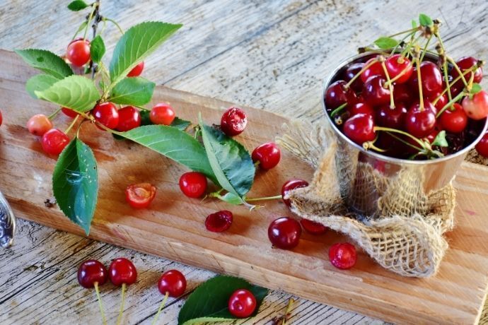 Cerejas e galhos com cerejas em uma superfície de madeira