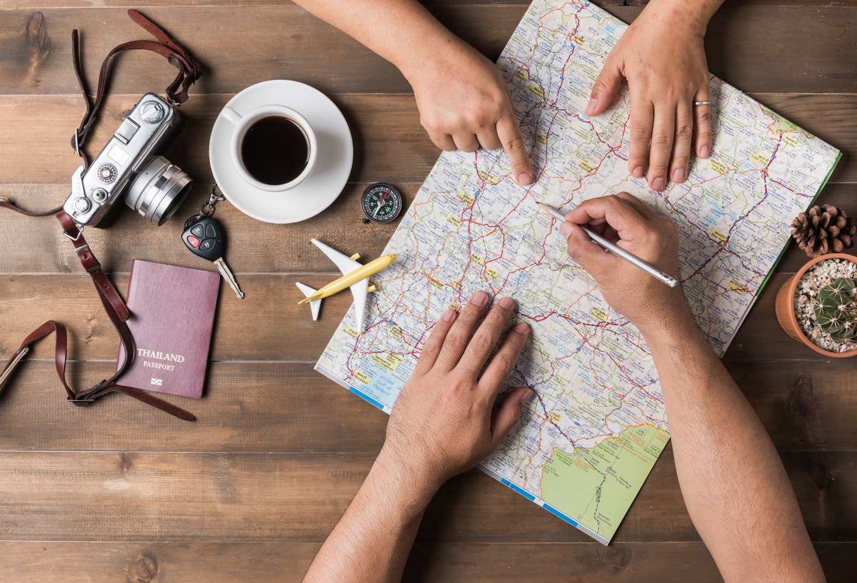 Pessoas escrevendo em um mapa de estradas de país estrangeiro sobre uma mesa de madeira.