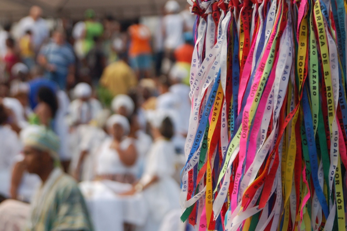 Fitinhas do senhor do Bonfim em primeiro plano. Em segundo plano, fiéis do Candomblé em comemoração.